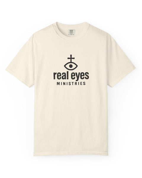 Beige t-shirt with 'real eyes ministries' logo on a white background