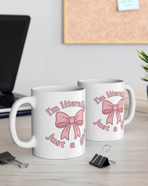 Two white mugs with pink bows and text on a desk with office supplies.