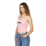 Woman wearing a pink tank top with black heart designs and blue jeans on a white background