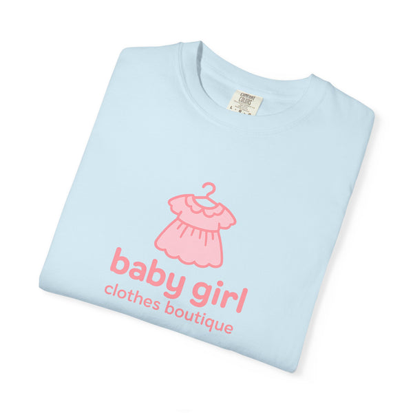 Folded light blue shirt with pink dress graphic and text on a white background
