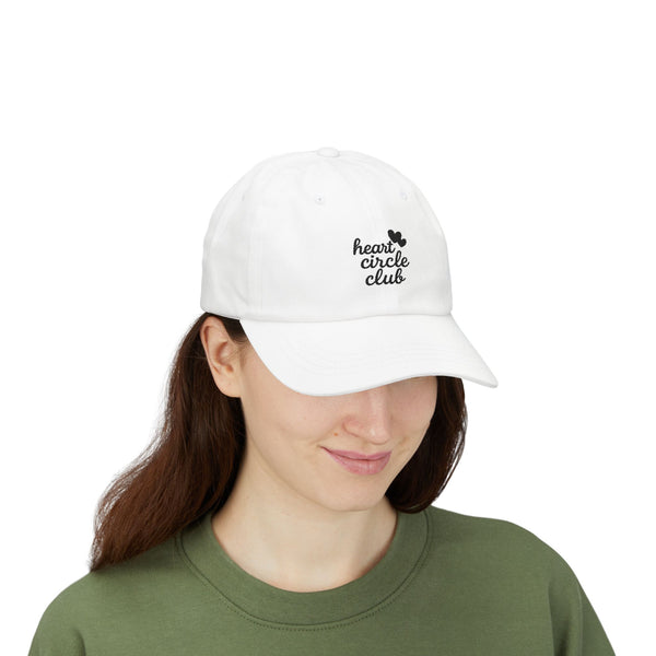 Person wearing a white cap with 'heart circle club' text on a white background