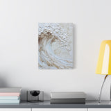 Abstract white wall art on a white wall above a shelf with books and a lamp.