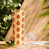 Tumbler with pixelated fire design on a wooden surface with plants in the background
