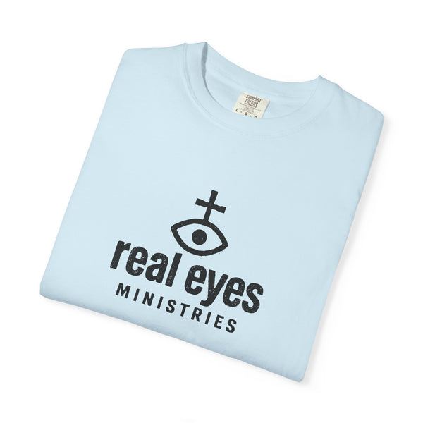Light blue t-shirt with 'real eyes MINISTRIES' logo on a white background