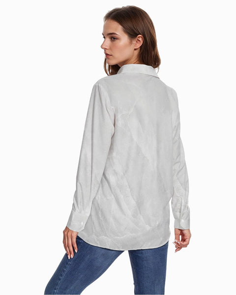 Woman wearing a light gray button-up shirt and blue jeans on a white background