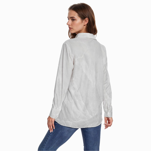 Woman wearing a light gray button-up shirt and blue jeans on a white background