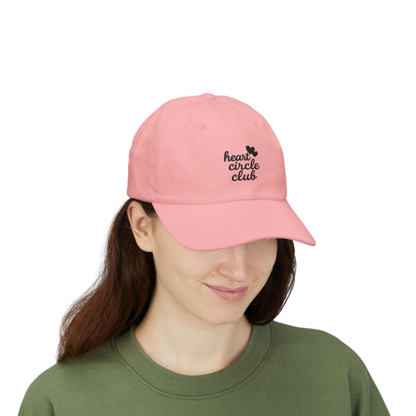 Person wearing a pink cap with 'heart circle club' text on a white background