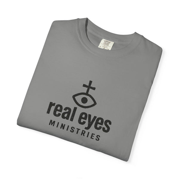 Folded gray t-shirt with 'real eyes MINISTRIES' logo on a white background