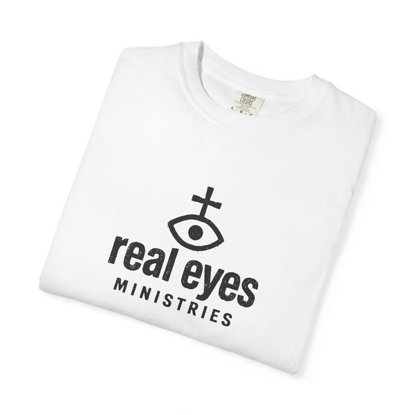 White t-shirt with 'real eyes MINISTRIES' logo on a white background