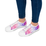White sneakers with colorful tie-dye pattern worn with blue jeans on a white background
