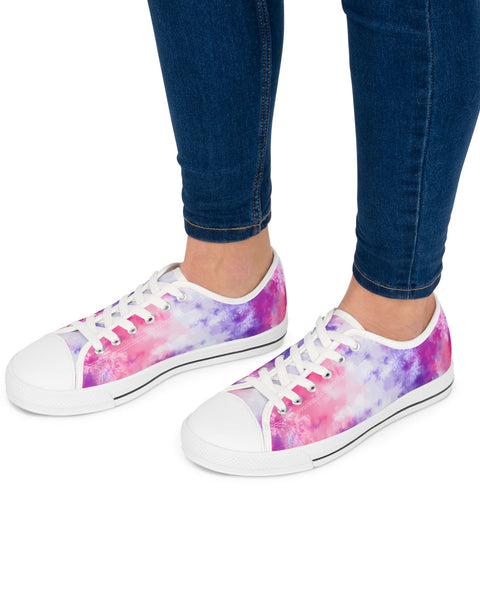 White sneakers with colorful tie-dye pattern worn with blue jeans on a white background