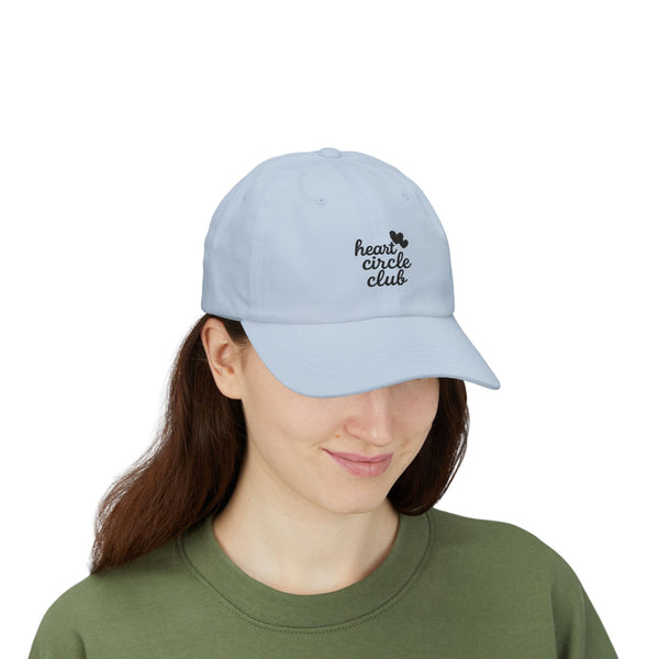 Person wearing a light blue cap with 'heart circle club' text on a white background
