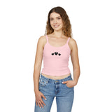 Woman wearing a pink tank top with black heart designs and blue jeans on a white background