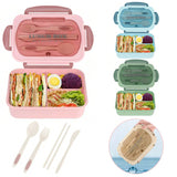 Pink and green bento boxes with compartments filled with food and utensils on a white background.