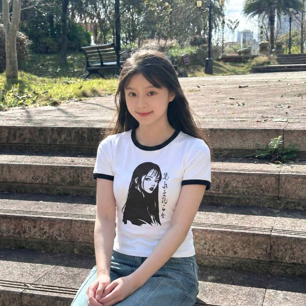 Woman wearing a white t-shirt with a manga design, sitting on steps outdoors.