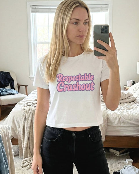 Person wearing a white t-shirt with 'Respectable Crashout' text in a bedroom.
