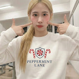 Girl wearing a cute white Christmas sweatshirt with 'Peppermint Lane' design