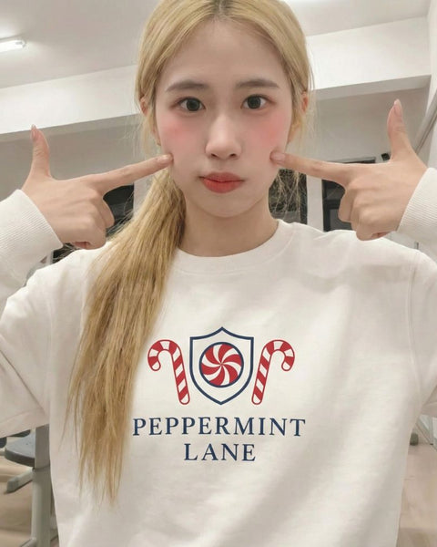 Girl wearing a cute white Christmas sweatshirt with 'Peppermint Lane' design