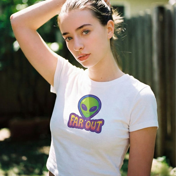 Woman wearing a white t-shirt with an alien graphic and 'FAR OUT' text outdoors.