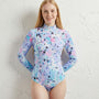 Person wearing a colorful long-sleeve swimsuit against a textured white background