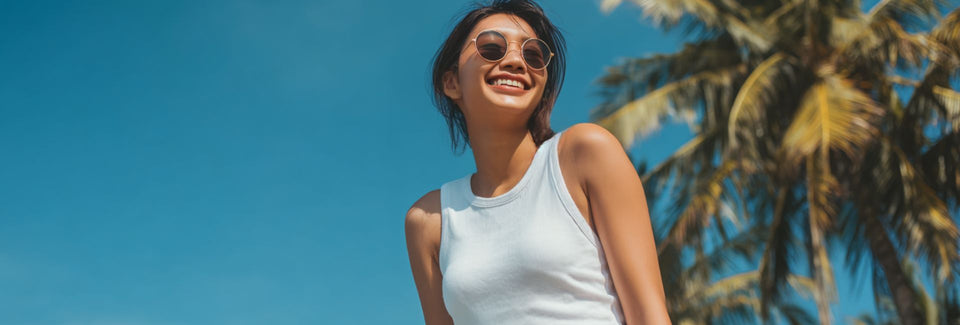  Woman wearing sunglasses against a blue sky with palm trees